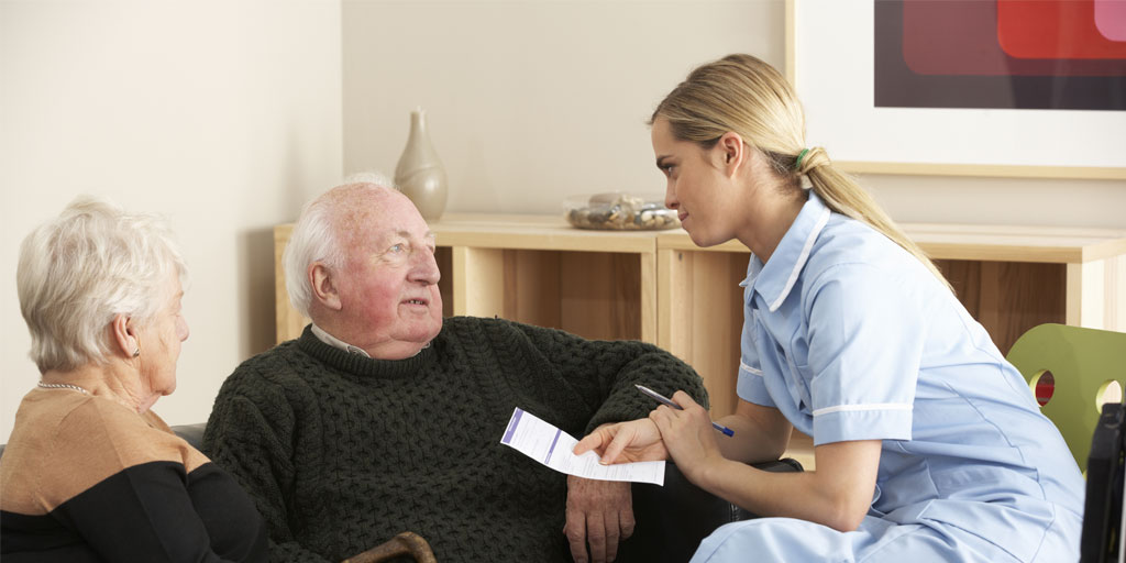 A nurse discussing care notes with an elderly couple in their home, demonstrating CareHubSupport's supportive approach to supported living
